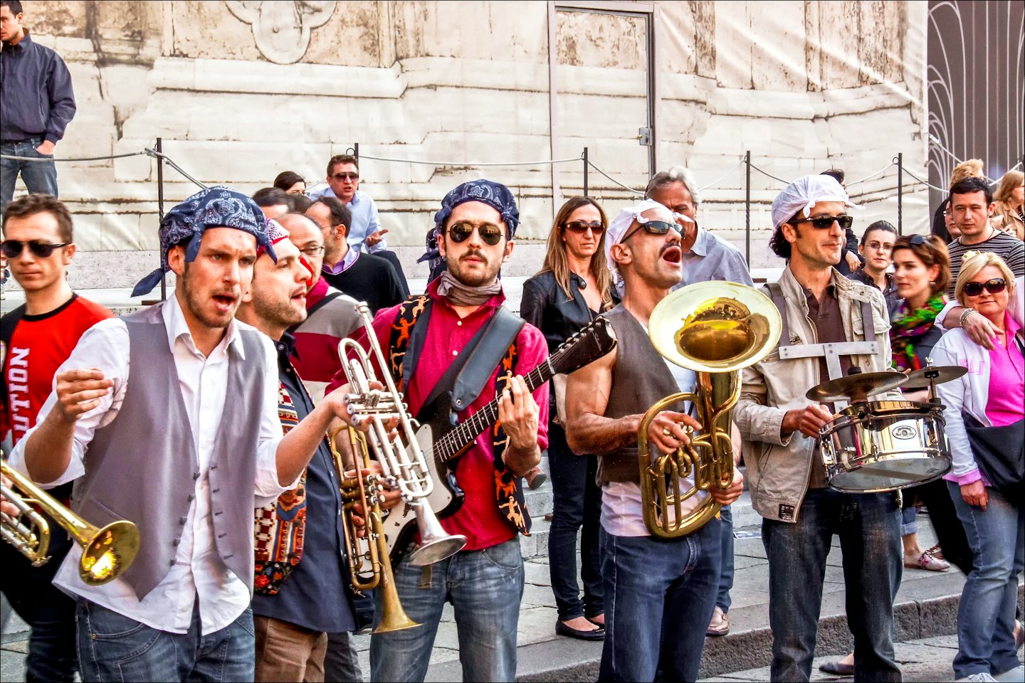 Musicisti di strada suonano tromba, chitarra e tuba per gli spettatori.